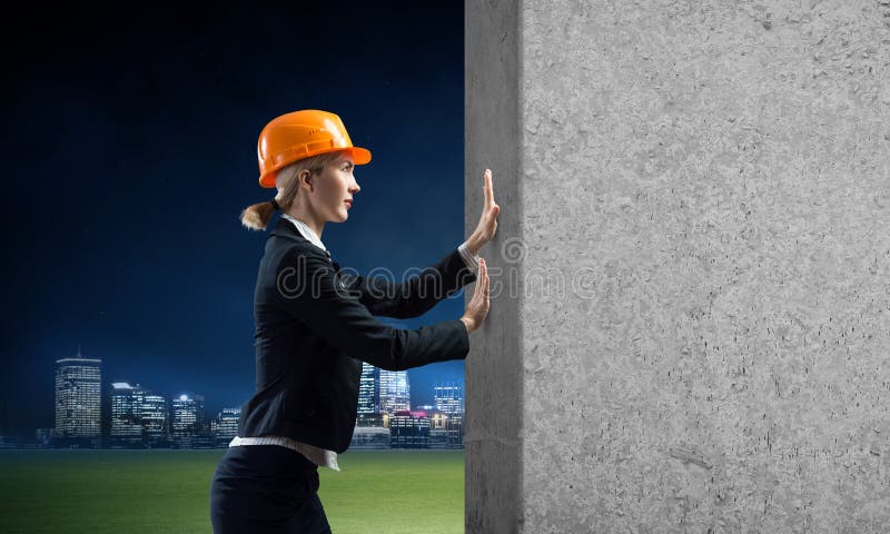 Vacker kvinnlig arkitekt som skjuter på betongväggen