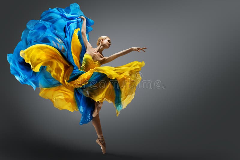 Vacker kvinnlig balettdansare som hoppar i luften i färglös fladderklänning. underbar ballerina som dansar i gul blå gås royaltyfri bild