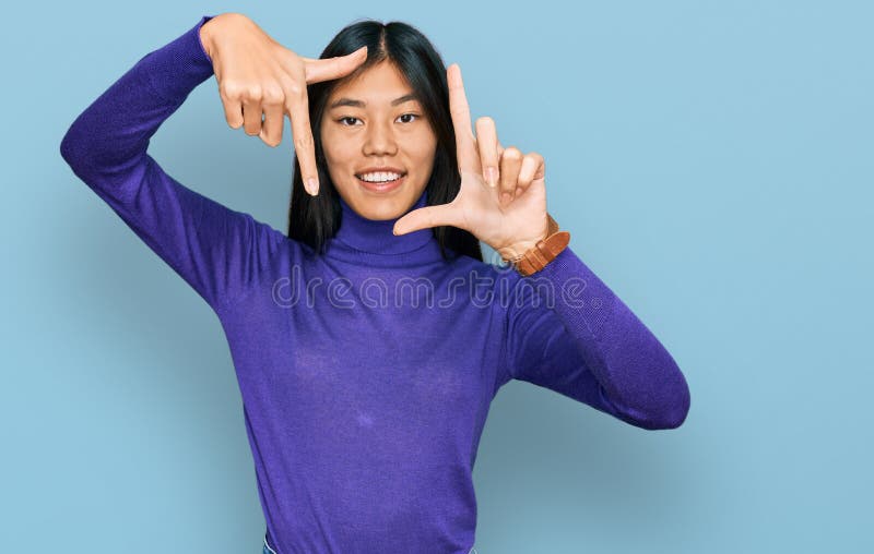Vacker ung asiatisk kvinna som bär fritidskläder leende som gör en ram med händer och fingrar med lyckligt ansikte arkivfoto