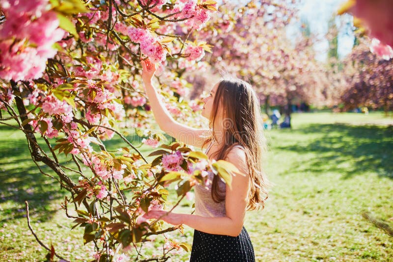 Vacker ung kvinna på solvårsdagen i parken under körsbärssäsongen royaltyfri foto