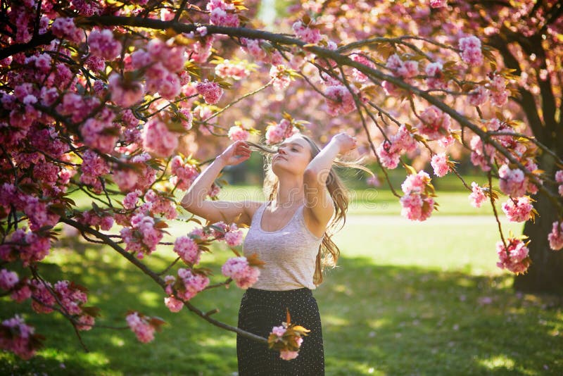 Vacker ung kvinna på solvårsdagen i parken under körsbärssäsongen royaltyfri bild