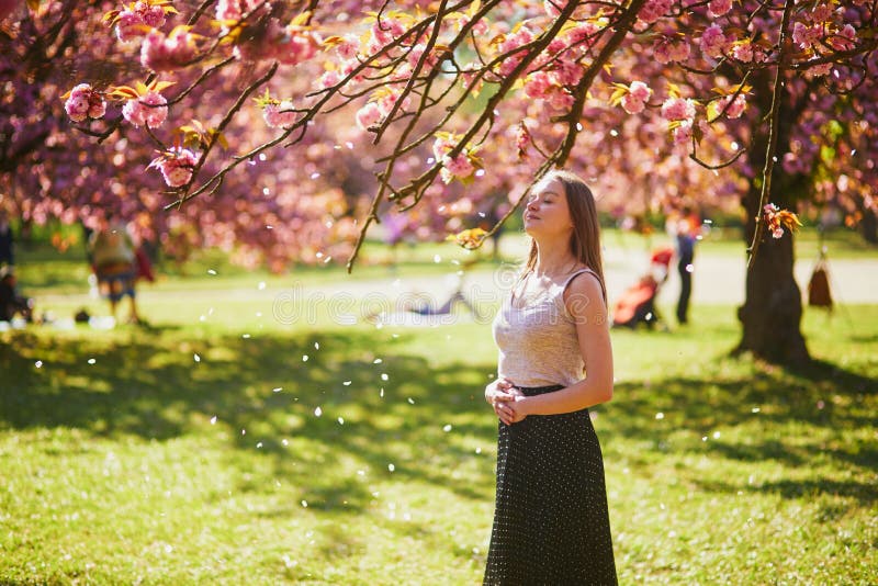 Vacker ung kvinna på solvårsdagen i parken under körsbärssäsongen royaltyfri fotografi