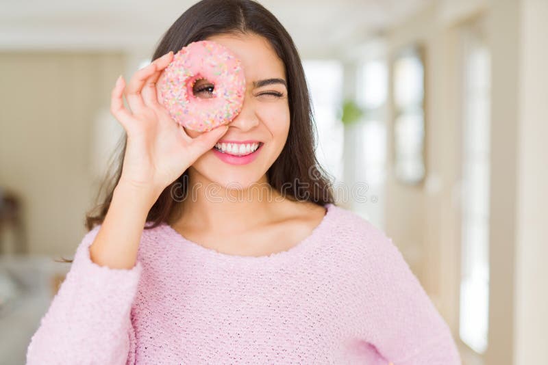 Vacker ung kvinna som ler och tittar igenom rosa på ögat