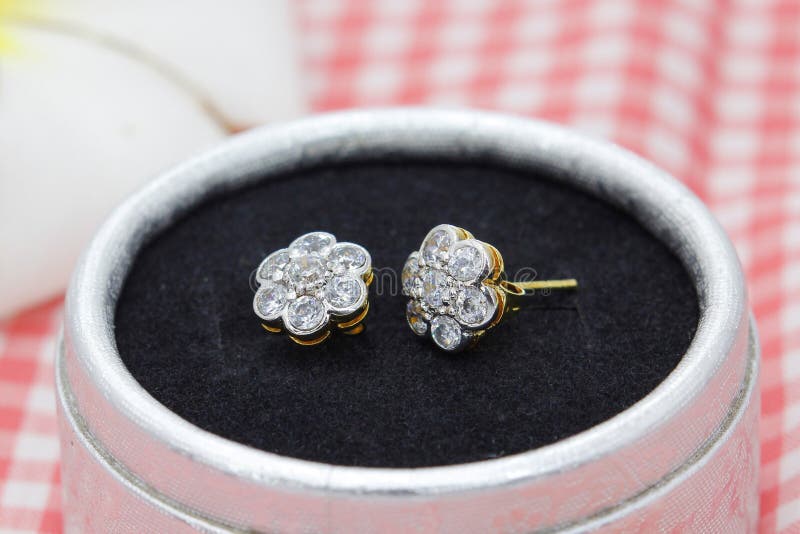Vackra guldörhängen som dekorerats med diamant i blomform i smyckeboxen royaltyfri foto