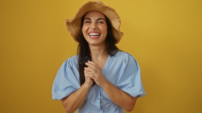 Vackra kvinnor som ler över en isolerad gul bakgrund med hatt och blå blus arkivfoto