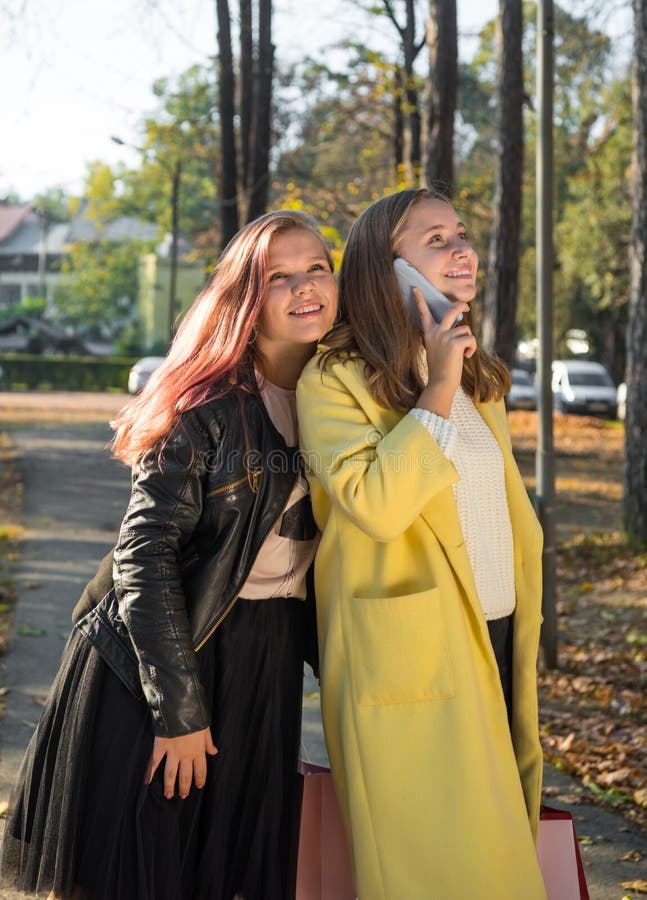 Vackra tonårsflickor som har kul på höstgatan på suunydagen royaltyfri bild