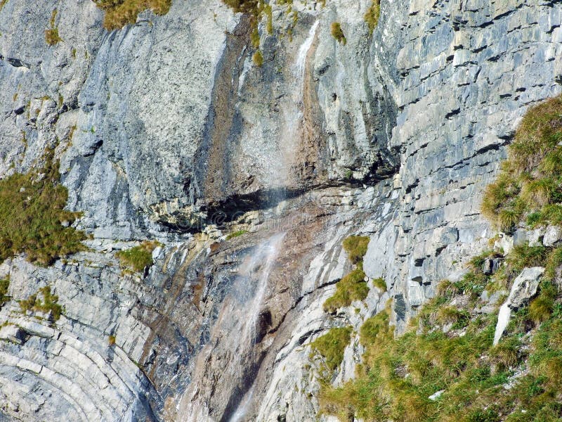 Vackra årstidsbetingade vattenfall under alpina klippfalknisturm i strutsbergsmassivet vid strutsgränsen eller raetikon grenzmassi