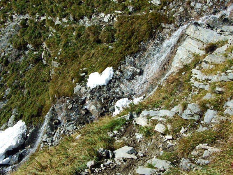 Vackra årstidsbetingade vattenfall under alpina klippfalknisturm i strutsbergsmassivet vid strutsgränsen eller raetikon grenzmassi