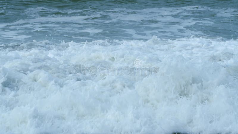 Vackra årstidsvågor som rullar till stranden. starka vindar skjuter runt sand och våldsamma vågor på stranden. långsam rörelse.