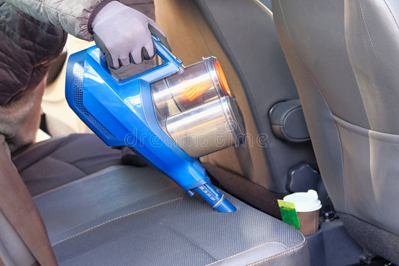 Vacuum Cleaner in Hands of Driver. Cleaning of Interior of the Car with