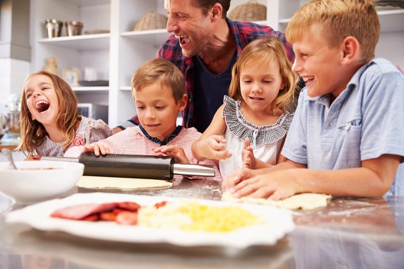 Vader die pizza met zijn jonge geitjes maken stock fotografie Vader die pizza met zijn jonge geitjes maken stock fotografie
