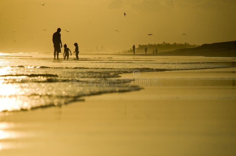 Vader en twee jonge geitjes die op het strand spelen royalty-vrije stock afbeeldingen Vader en twee jonge geitjes die op het strand spelen royalty-vrije stock afbeeldingen