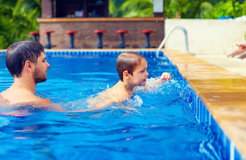 Vader en zoon die in pool bij de zomervakantie zwemmen royalty-vrije stock fotografie Vader en zoon die in pool bij de zomervakantie zwemmen royalty-vrije stock fotografie