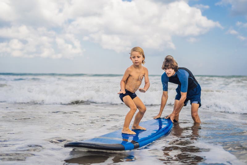 Vader of instructeur die zijn 4 éénjarigenzoon onderwijzen hoe te binnen te surfen stock afbeeldingen Vader of instructeur die zijn 4 éénjarigenzoon onderwijzen hoe te binnen te surfen stock afbeeldingen