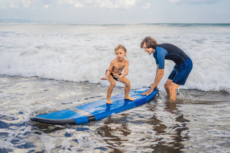 Vader of instructeur die zijn 4 éénjarigenzoon onderwijzen hoe te binnen te surfen royalty-vrije stock foto Vader of instructeur die zijn 4 éénjarigenzoon onderwijzen hoe te binnen te surfen royalty-vrije stock foto