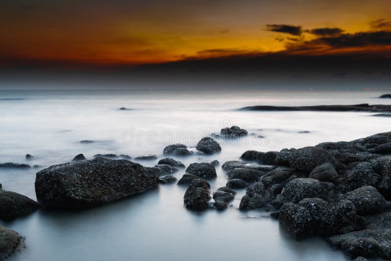 Vagga och havet i f?rgen av solnedg?ngtid arkivfoto Vagga och havet i f?rgen av solnedg?ngtid arkivfoto