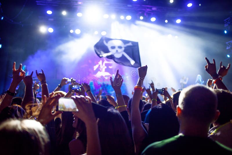 Vagga upp konserten, händerna Folket är lyckligt i klubban, piratkopierar flaggan framme av ljus royaltyfria foton Vagga upp konserten, händerna Folket är lyckligt i klubban, piratkopierar flaggan framme av ljus royaltyfria foton