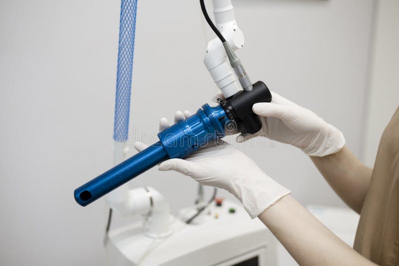 Female doctor is holding a laser used for vaginal treatment of incontinence. Visible ray of laser beam in a hand shaped as a vaginal entrance. Laser control screen seen in the background. Female doctor is holding a laser used for vaginal treatment of incontinence. Visible ray of laser beam in a hand shaped as a vaginal entrance. Laser control screen seen in the background.