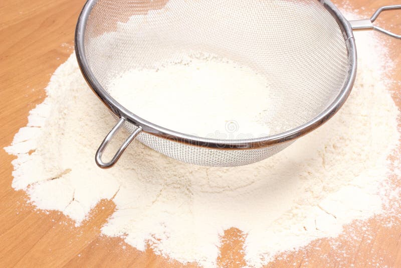 Vagliare la farina di frumento al il setaccio immagine stock libera da diritti Vagliare la farina di frumento al il setaccio immagine stock libera da diritti