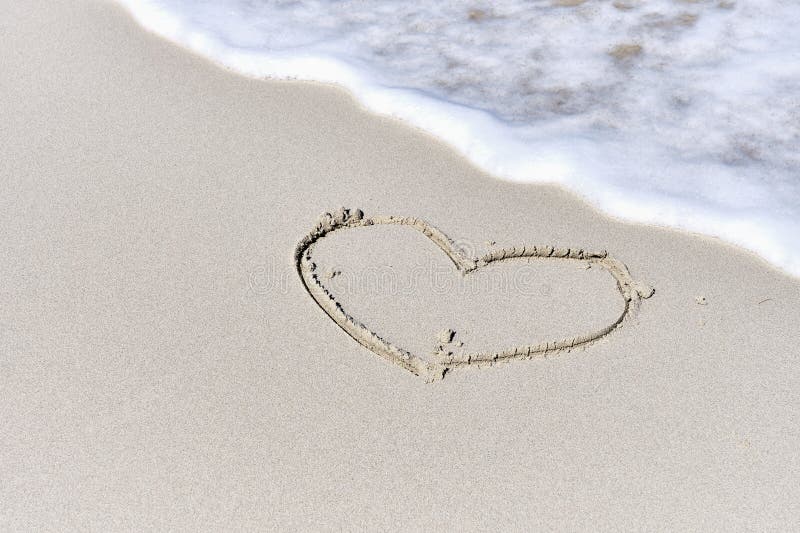 Foamy wave, washing over light sand with outline drawing of heart symbol. Tropical beach. Copy space. Foamy wave, washing over light sand with outline drawing of heart symbol. Tropical beach. Copy space