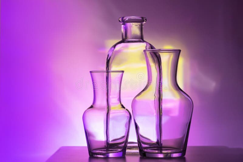 Vajilla transparente de cristal - botellas de diversos tamaños, de tres pedazos en un multicolor hermoso, amarillo, lila y fotografía de archivo Vajilla transparente de cristal - botellas de diversos tamaños, de tres pedazos en un multicolor hermoso, amarillo, lila y fotografía de archivo