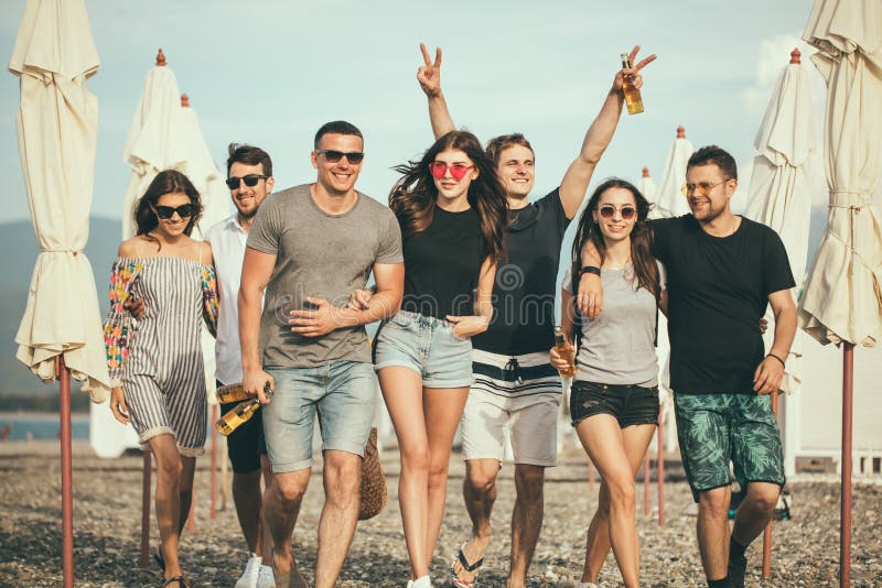vakantie, vakantie groep die vrienden die pret op strand hebben, drinkt bier, het glimlachen en het koesteren de lopen stock foto vakantie, vakantie groep die vrienden die pret op strand hebben, drinkt bier, het glimlachen en het koesteren de lopen stock foto
