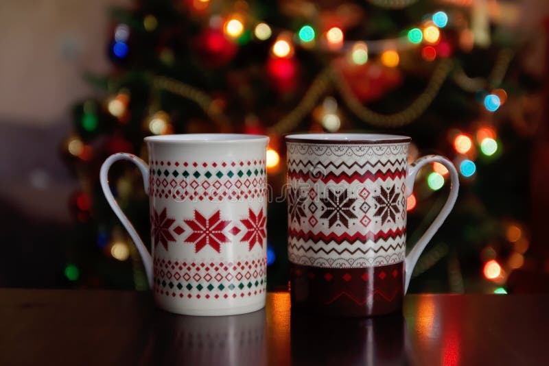 holidays, christmas, winter, food and drinks concept - close up of candy canes and cups on wooden table over lights. holidays, christmas, winter, food and drinks concept - close up of candy canes and cups on wooden table over lights.