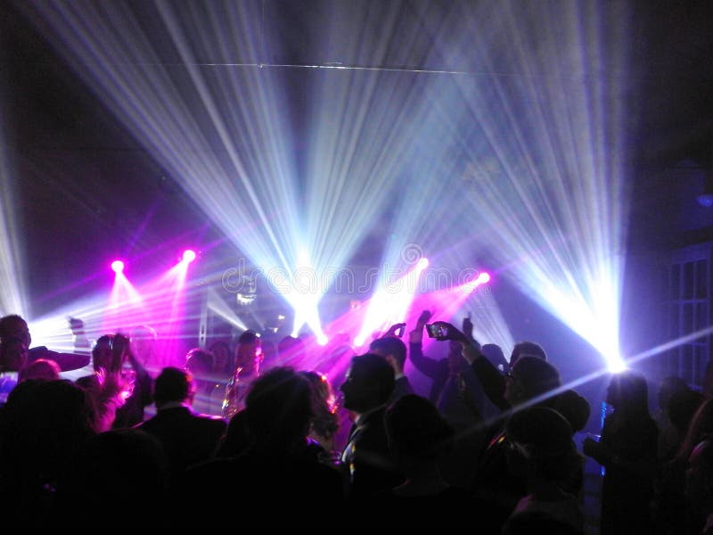 Abstract image of people silhouettes under spotlights and neon lights in a party