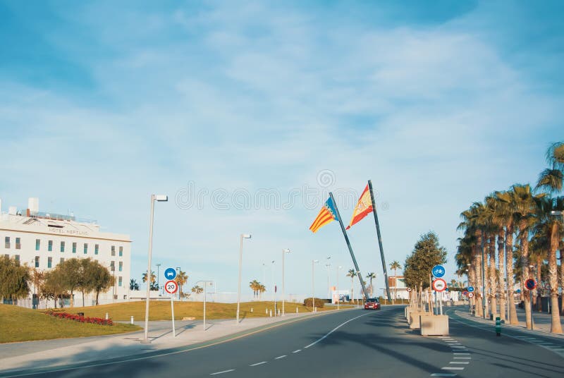 VALENCIA, SPAIN - FEBRUARY 3, 2016: A road to Valencia beach, palms and two big spanish and valencian flags. VALENCIA, SPAIN - FEBRUARY 3, 2016: A road to Valencia beach, palms and two big spanish and valencian flags.