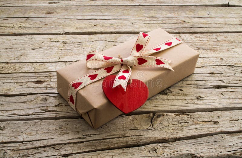 Valentine gift box and red heart shape tag on wooden board