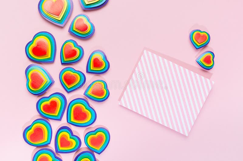 Valentine lgbt fond festif arc-en-ciel coeurs lumineux avec papier rayé vierge pour texte sur fond rose pastel vue du haut. images stock