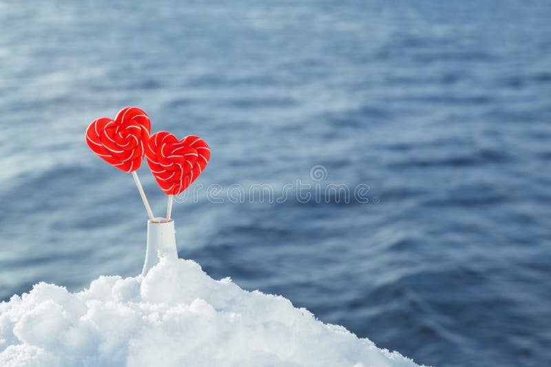 Hearts lollipops in the snow on the background of sea waves. Romantic date, Declaration of love, Valentine`s day