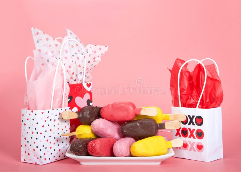 Valentine`s day gift bags on pink background with cake popsicles