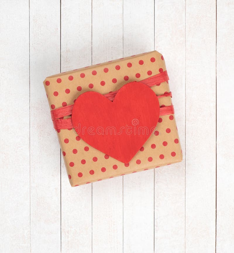 Valentine`s Day wrapped Gift with a Red Heart Tag with empty copy space for your love message.  The background is White, Vertical