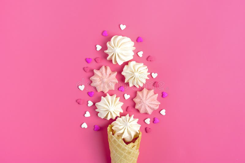 Valentine`s postcard - meringue and candy in the shape of a heart and ice cream cone on a pink background