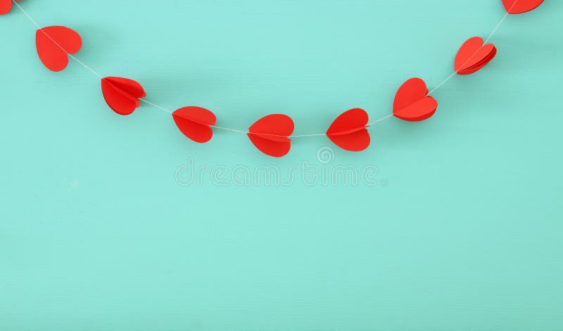 Valentine&x27;s day background. hearts garland hanging in front of blue wooden background.