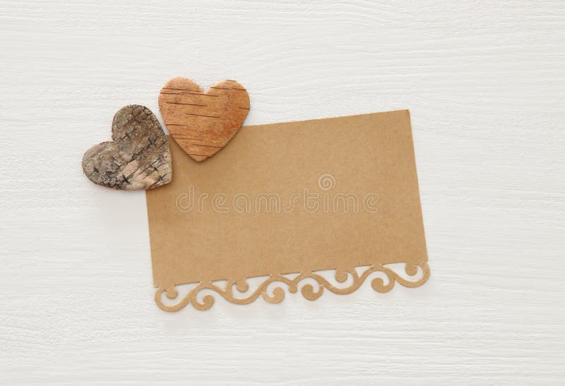 Valentine& x27;s day concept. hearts cutted from tree trunk and vintage paper note over wooden white background.