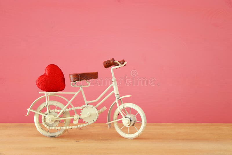 Valentine& x27;s day romantic background with white vintage bicycle toy and heart on it over wooden table.