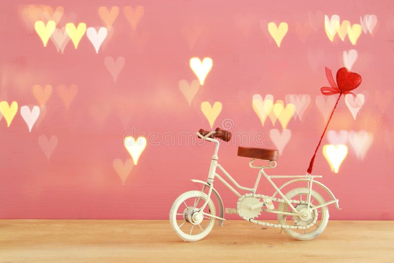 Valentine& x27;s day romantic background with white vintage bicycle toy and heart on it over wooden table.