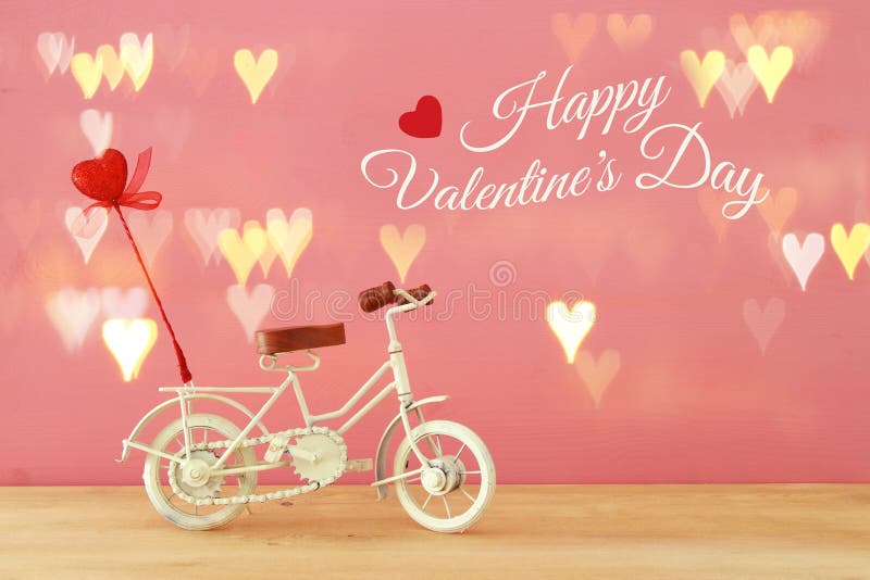 Valentine& x27;s day romantic background with white vintage bicycle toy and heart on it over wooden table.