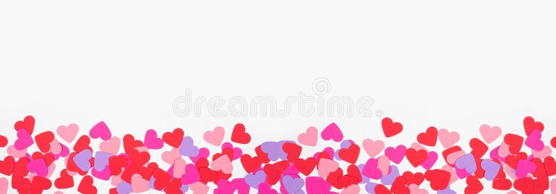 Valentines Day bottom border with paper heart confetti. Top view over a white banner background. Copy space. Valentines Day bottom border with paper heart confetti. Top view over a white banner background. Copy space