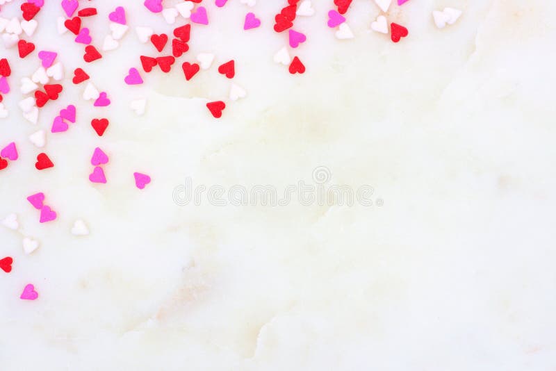 Valentines Day candy heart sprinkles corner border over a white textured background