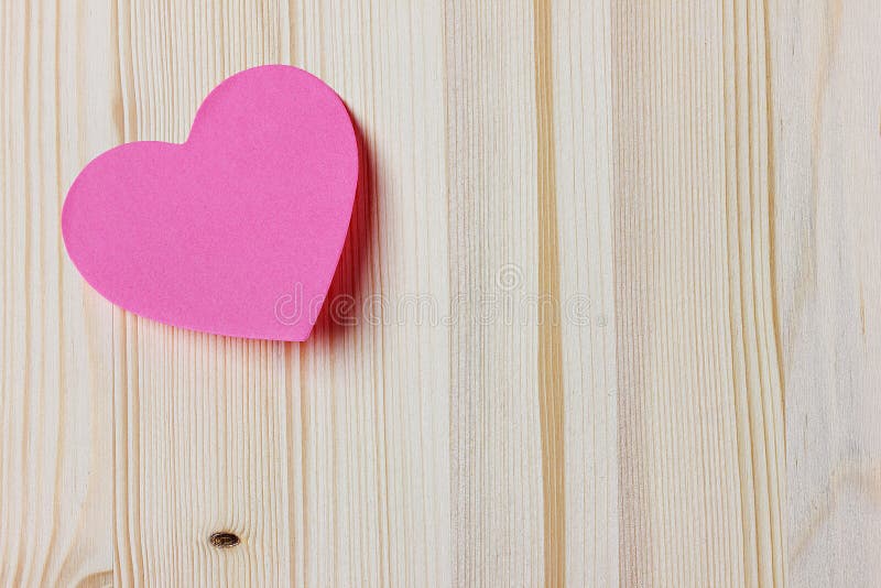 Valentines day card with sticky note in the shape of a heart on a wooden background, love message on Valentines day