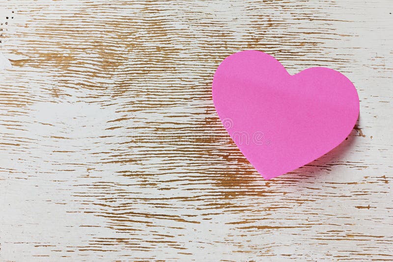 Valentines day card with sticky note in the shape of a heart on a wooden background, love message on Valentines day