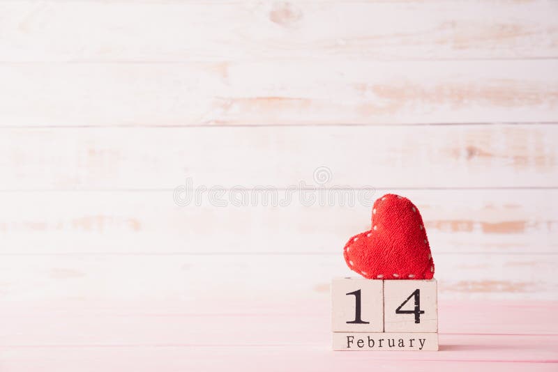 Valentines day concept. February 14 text on wooden block with handmade red heart on white wooden background