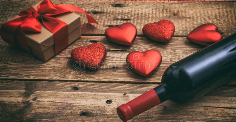 Valentines day. Red wine bottle, a gift and hearts on wooden background royalty free stock image Valentines day. Red wine bottle, a gift and hearts on wooden background royalty free stock image