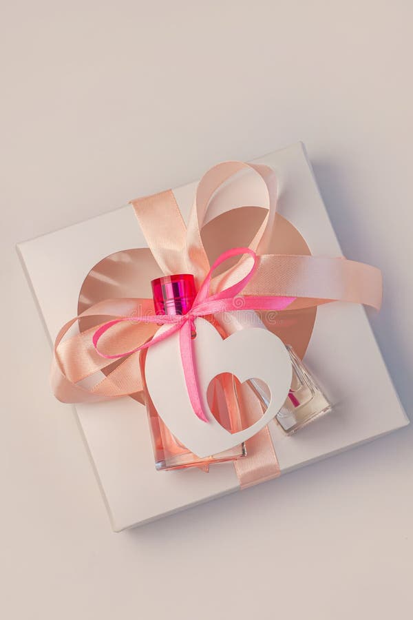 Valentines Day creative concept flatlay.Gift box mockup, pink perfume bottle, nail polish with ribbon on white background.