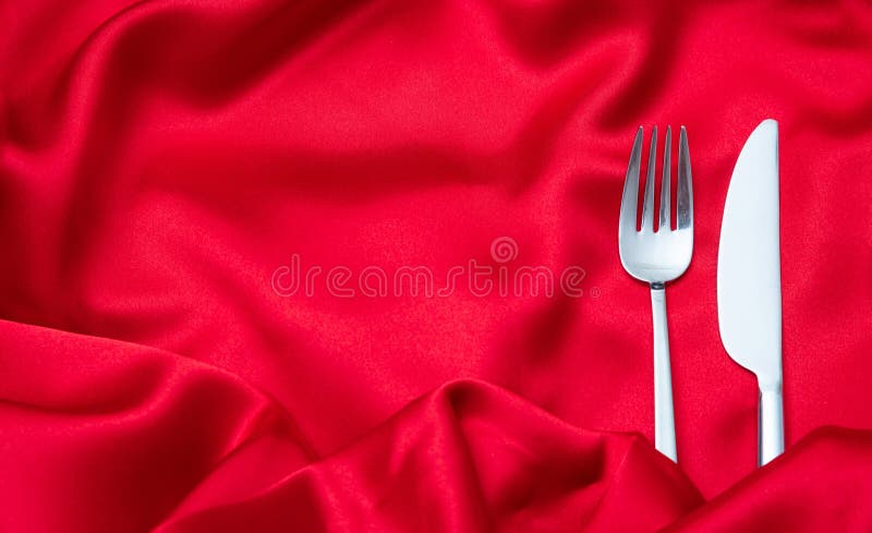 Valentines dinner, Cutlery, fork and knife on red satin background, copy space, top view