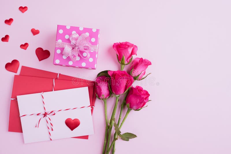 Valentines day and love concept. Pink roses, gift box with red heart and red pink letter cover on pink background stock image Valentines day and love concept. Pink roses, gift box with red heart and red pink letter cover on pink background stock image