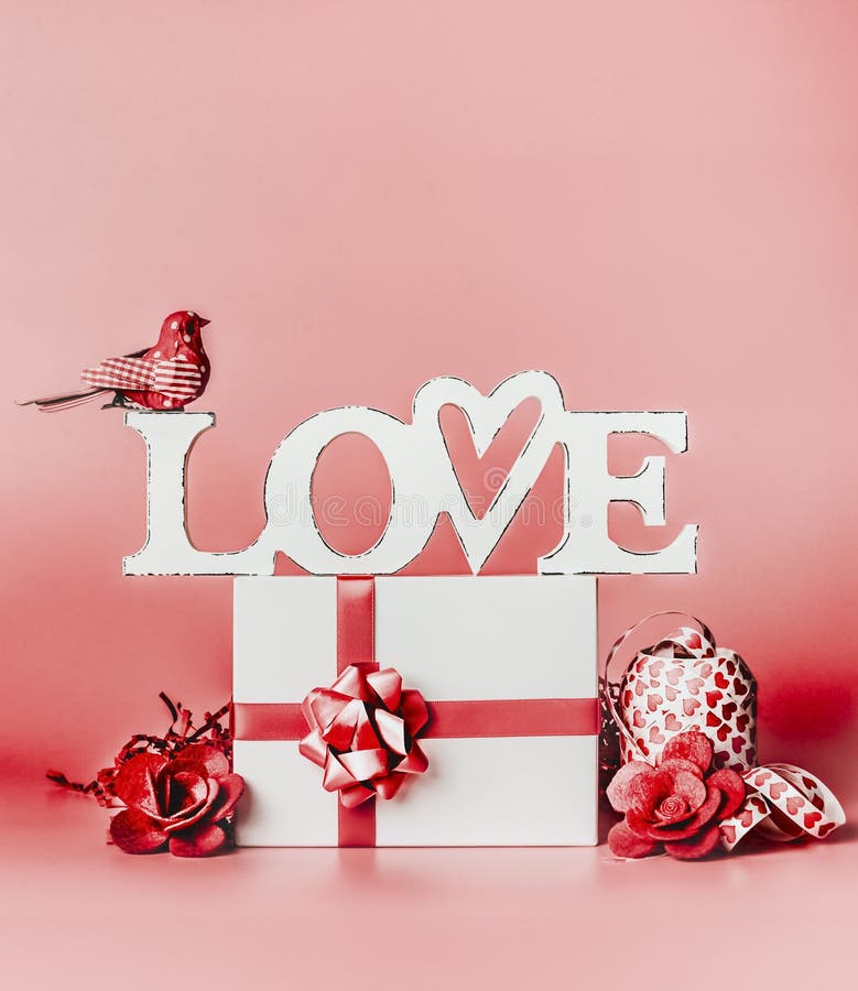 Valentines day romantic still life composition with word Love and greeting setting: gift box, ribbon, and decoration at red backgr royalty free stock images Valentines day romantic still life composition with word Love and greeting setting: gift box, ribbon, and decoration at red backgr royalty free stock images